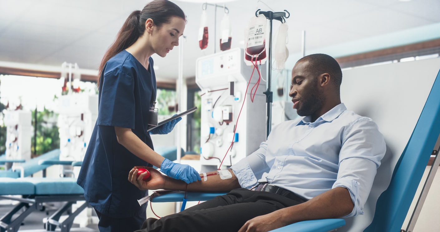 phlebotomist caring for blood donor carefully considering blood draw safety 